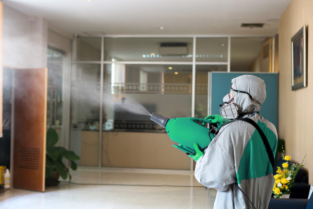 Homem pulverizando produto de sanitização em um ambiente corporativo.